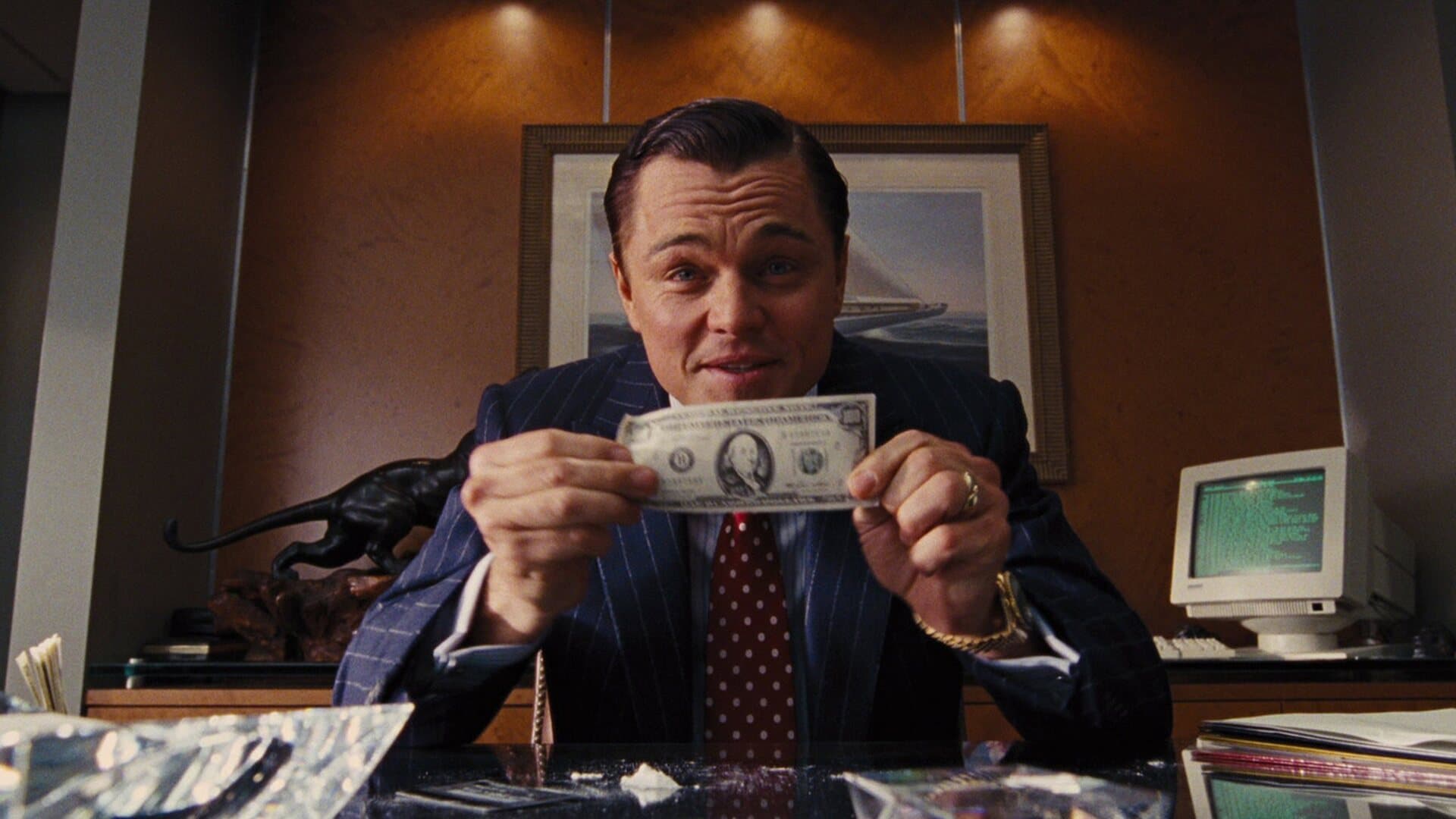 Jordan Belfort holding a banknote in his office